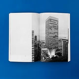 Open book showing a black and white photograph of a cityscape with a tall building on a blue background