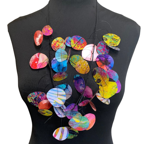 A multi-colored necklace with circular pendants displayed on a mannequin torso.